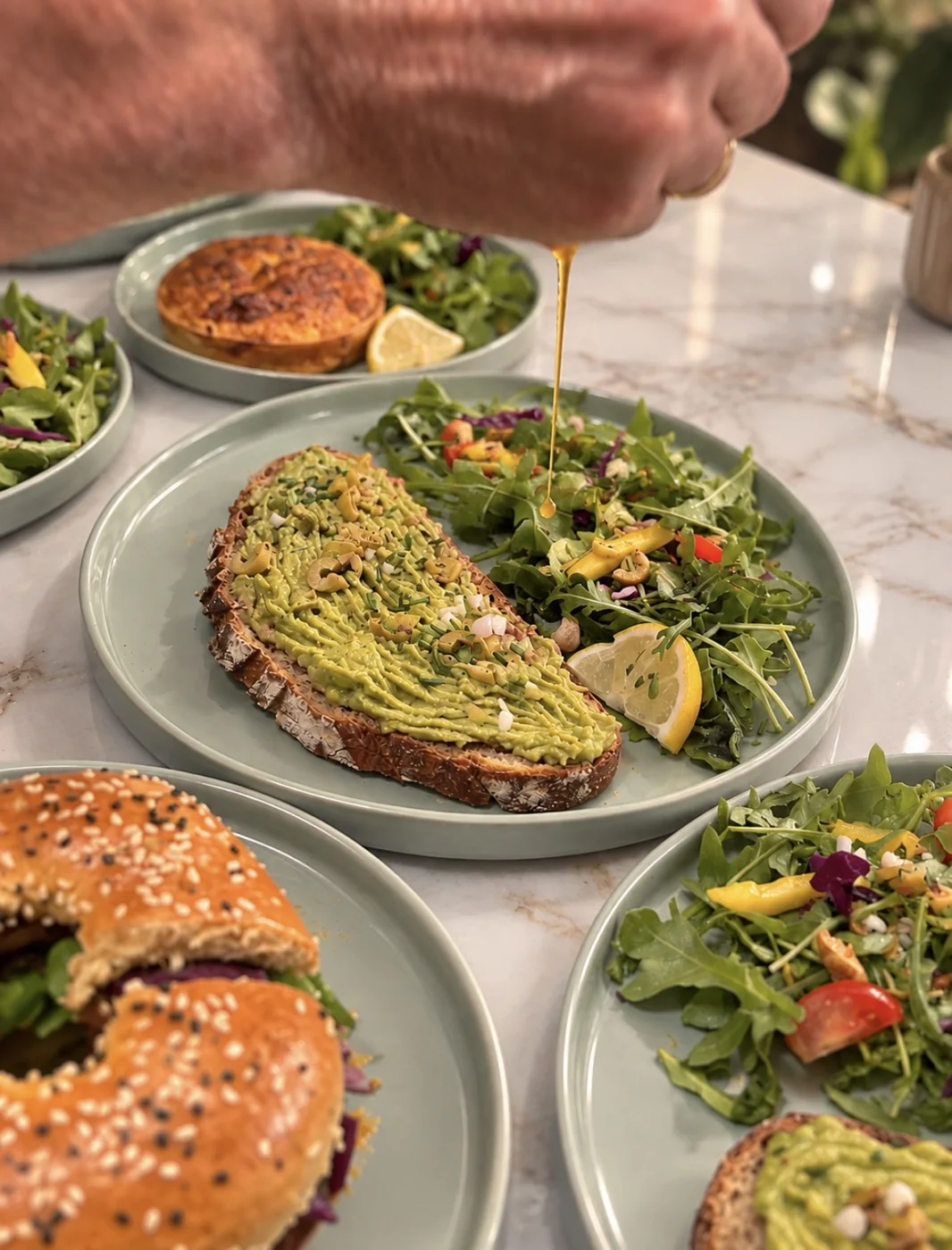 Tartine d'avocat sur pain au levain, salade d'roquette et bagel garni